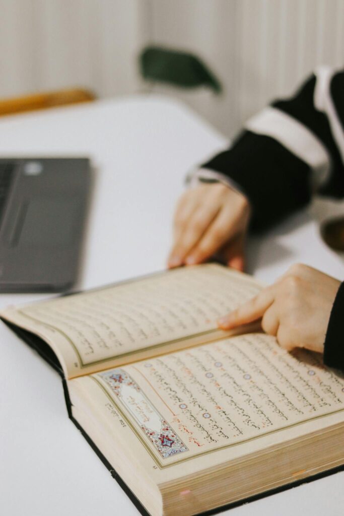 A child studies a religious text at a desk, focusing on learning and education.