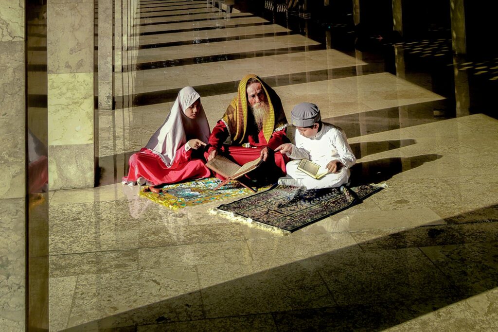 A serene moment of three people engaged in prayer in a beautifully lit mosque corridor.